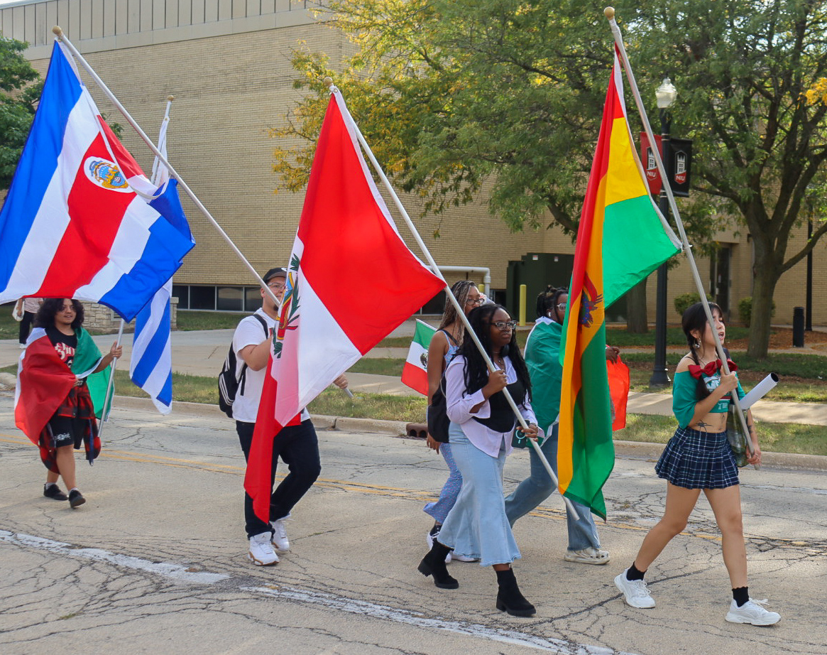 A group of students march on Normal Road while holding flags from different Latin American countries. To celebrate Latino Heritage Month, students can tie-dye shirts at the Latino Resource Center on Thursday. (Marco Alvarez | Northern Star) 