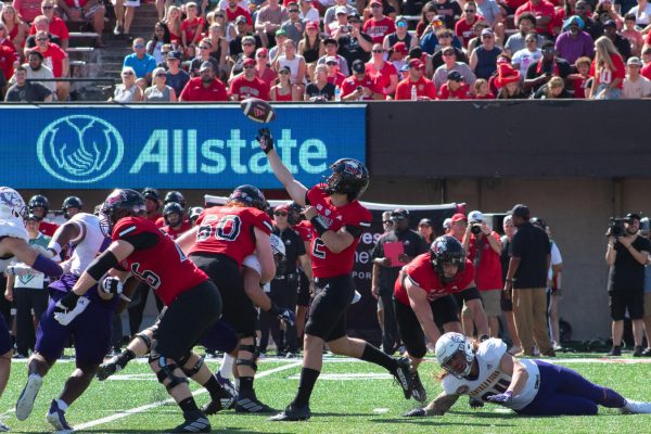 Ethan Hampton (2), redshirt junior quarterback, passes the ball over the defensive line to Gavin Williams (21), redshirt senior running back for a first down and 8-yard gain during the second quarter. The field saw no break from the sun until the third quarter when a shadow was cast that split the field in half from endzone to endzone and caused visibility issues. (Totus Tuus Keely | Northern Star)

