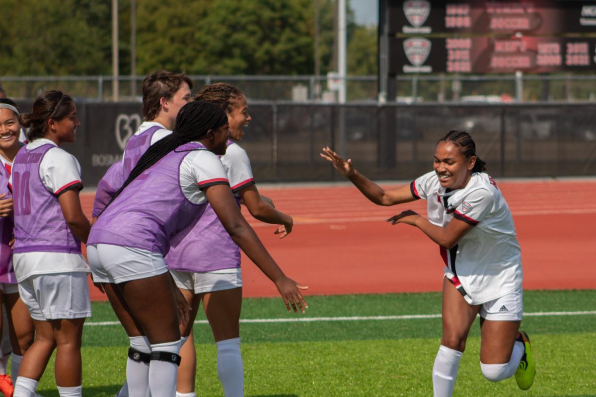 Junior forward Amber Best (right) is congratulated by the NIU women’s soccer team on the sidelines after her goal in the second period. NIU women's soccer defeated Valparaiso University 2-1 on Sunday to win its sixth game of the season. (Totus Tuus Keely | Northern Star)