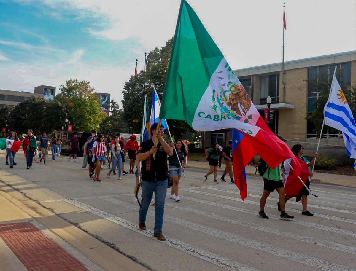 A group of students march on Normal Road while holding flags. In honor of Latino Heritage Month, the Latino Resource Center hosted their kick off parade at 4 p.m. on Monday. (Marco Alvarez | Northern Star)