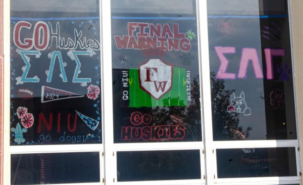 Three windows outside of the Holmes Student Center are painted with different designs at the “Paint the Windows” event. This week marks NIU’s 117th Homecoming where there will be various events all week around campus and DeKalb. (Sam Dion | Northern Star) 
