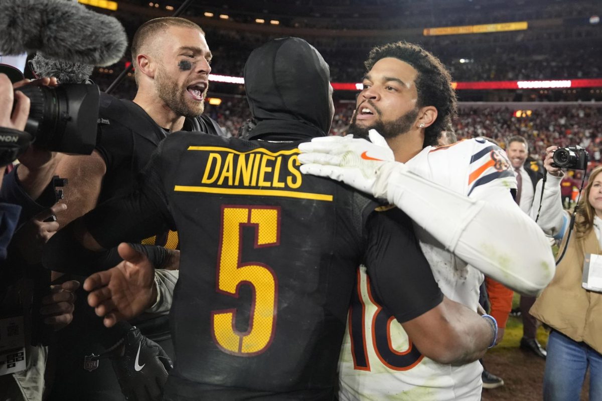 Washington Commanders quarterback Jayden Daniels (5) is congratulated by Chicago Bears quarterback Caleb Williams (18) after the Commanders won 18-15 on Sunday in Landover, Maryland. Assistant Sports Editor Edison Miller revisits his draft grades for the Bears' 2024 draft class. (Stephanie Scarbrough | AP Photo)