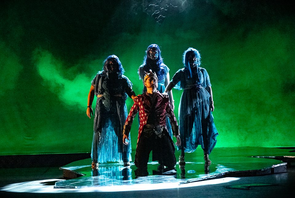 Three witches stand around Macbeth as he kneels. The School of Theatre and Dance performed "Macbeth" in the O'Connell Theatre. (Courtesy of Antonio Houston)