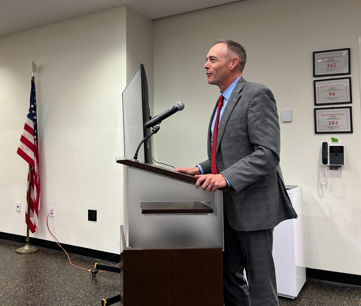 Matt Streb, chief of staff to NIU President Lisa Freeman and NIU political science professor, stands behind a podium and addresses the members of the DeKalb City Council. The sale of the property where the Greek Life Center will be built is set to close on Oct. 21. (Devin Oommen | Northern Star)