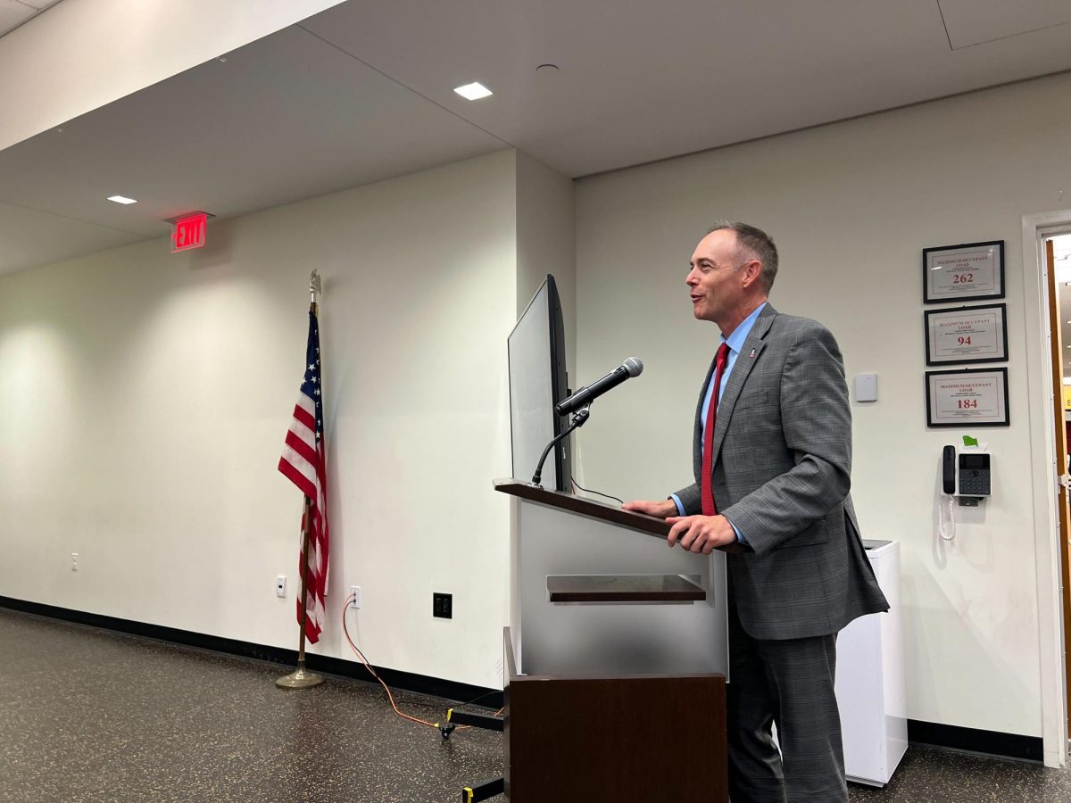 Matt Streb, chief of staff to NIU President Lisa Freeman and NIU political science professor, stands behind a podium and addresses the members of the DeKalb City Council. The sale of the property where the Greek Life Center will be built is set to close on Oct. 21. (Devin Oommen | Northern Star)