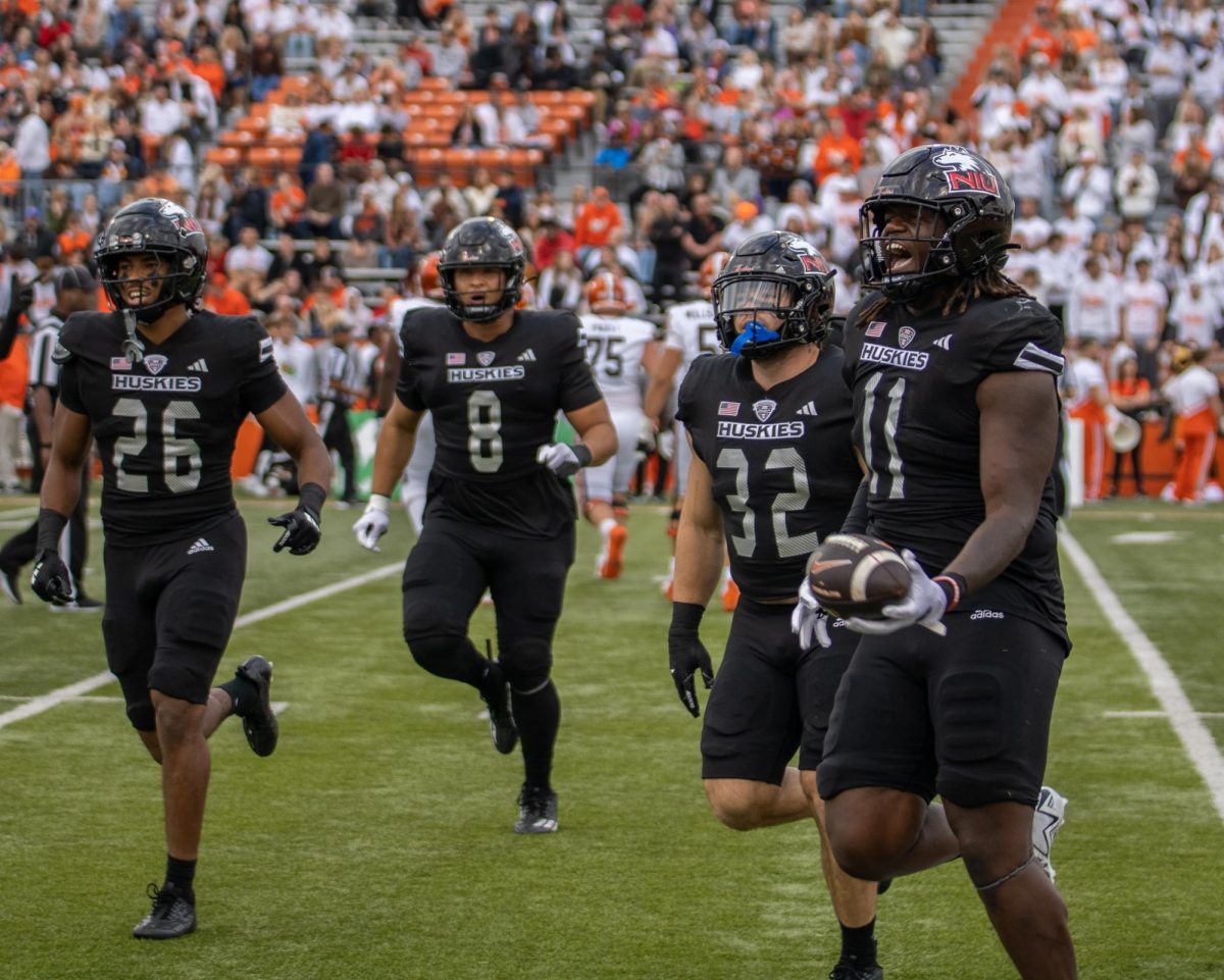 The Huskies' defense returns to its sideline celebrating after redshirt junior defensive end Jalonnie Williams (11) recovered a fumble during the second quarter of NIU's 17-7 win against Bowling Green State University at Doyt L. Perry Stadium in Bowling Green, Ohio. The Huskies trailed 7-3 in the first quarter before scoring 14 unanswered to earn the road victory. (Tim Dodge | Northern Star)