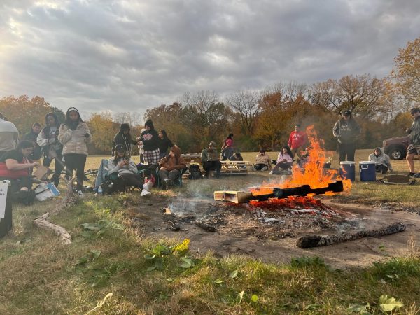 A group of students gather around a bonfire at the West Lagoon Tuesday. The Latino Resource Center in partnership with NIU Recreation hosted the Leyendas and Myths Bonfire event from 4 p.m. to 5:30 p.m. Tuesday at the West Lagoon. (Gray Edelstein | Northern Star)