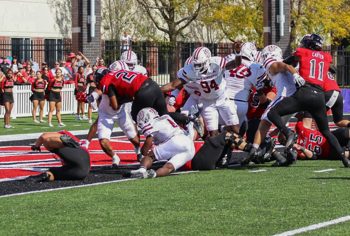 NIU redshirt senior running back Gavin Williams (21) dives into the endzone for a touchdown past the University of Massachusetts defense during the fourth quarter. Williams’ rushing touchdown extended the Huskies lead to 27-13. (Marco Alvarez | Northern Star)