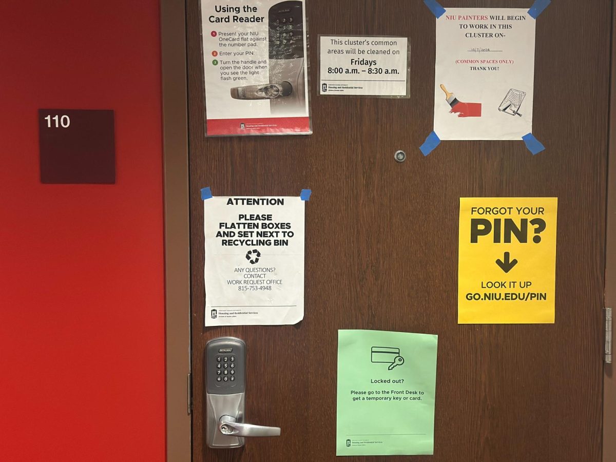 A card reader system keeps a dorm room door locked, while posters explain how students can use their OneCards to access their dorms. Residential halls have various methods of security, but Opinion Columnist Ethan Ernst encourages students to remember the individual choice to not let strangers into halls should serve as another layer of security. (Marco Alvarez | Northern Star)