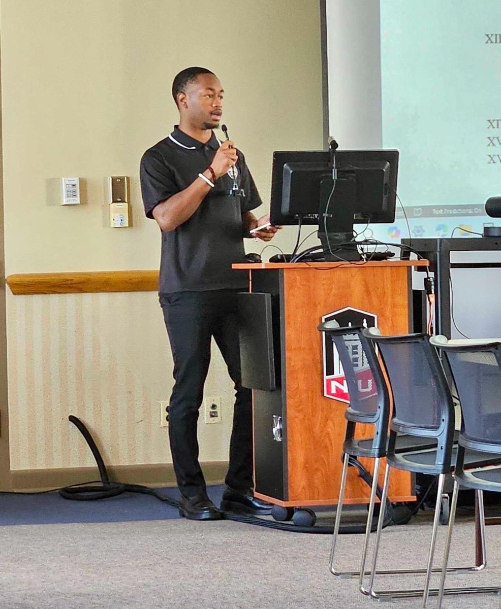 The Student Government Association president Ja'kobe Jones stands behind a podium and talks to the crowd at the SGA meeting on Friday. Jones talked about student engagement events that have happened so far throughout the semester. (Kahlil Kambui | Northern Star)