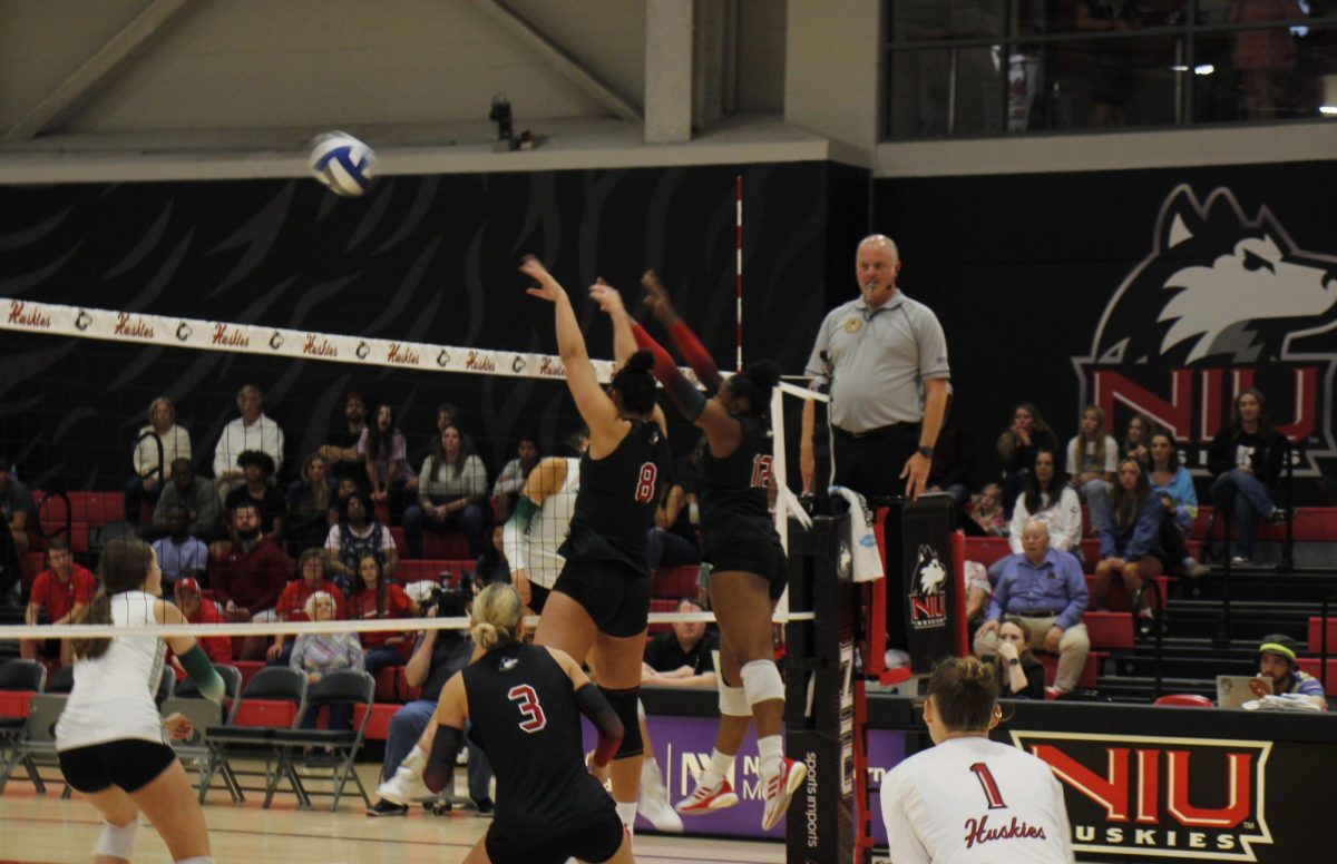 Freshman middle blocker Rylee Alvin (8) and junior right side Alexa Hayes (12) attempt a block on Oct. 11 at Victor E. Court. NIU volleyball was swept for the third-straight match as the Huskies lost to the Ball State University Cardinals on Friday. (Marco Alvarez | Northern Star)