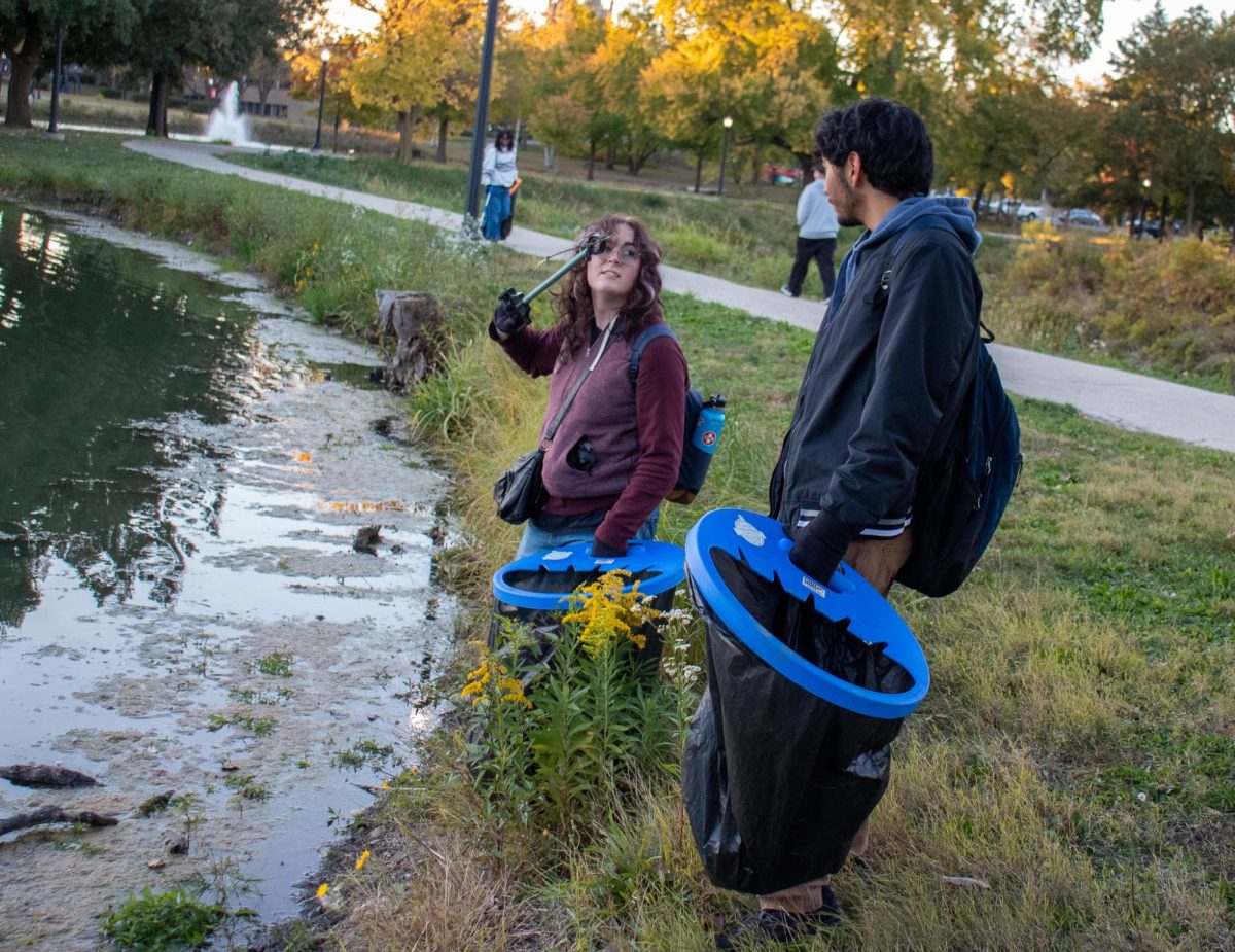 Andria Revolorio, a first-year psychology major, and Ellie Andries, a sophomore jazz studies major, pick up trash alongside the East Lagoon at the clean-up event Wednesday. The event was hosted from 5 p.m. to 7 p.m. (Marco Alvarez | Northern Star)