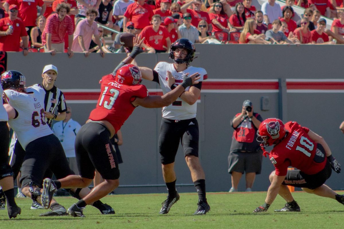 NIU redshirt junior quarterback Ethan Hampton (2) throws a pass under pressure from North Carolina State University redshirt junior defensive end Travali Price (13) in the third quarter of NIU’s 24-17 loss to NC State on Saturday at Carter-Finley Stadium in Raleigh, North Carolina. Hampton committed four turnovers – two fumbles and two interceptions – while taking a career-high four sacks in his sixth loss as the Huskies’ starting quarterback. (Totus Tuus Keely | Northern Star)