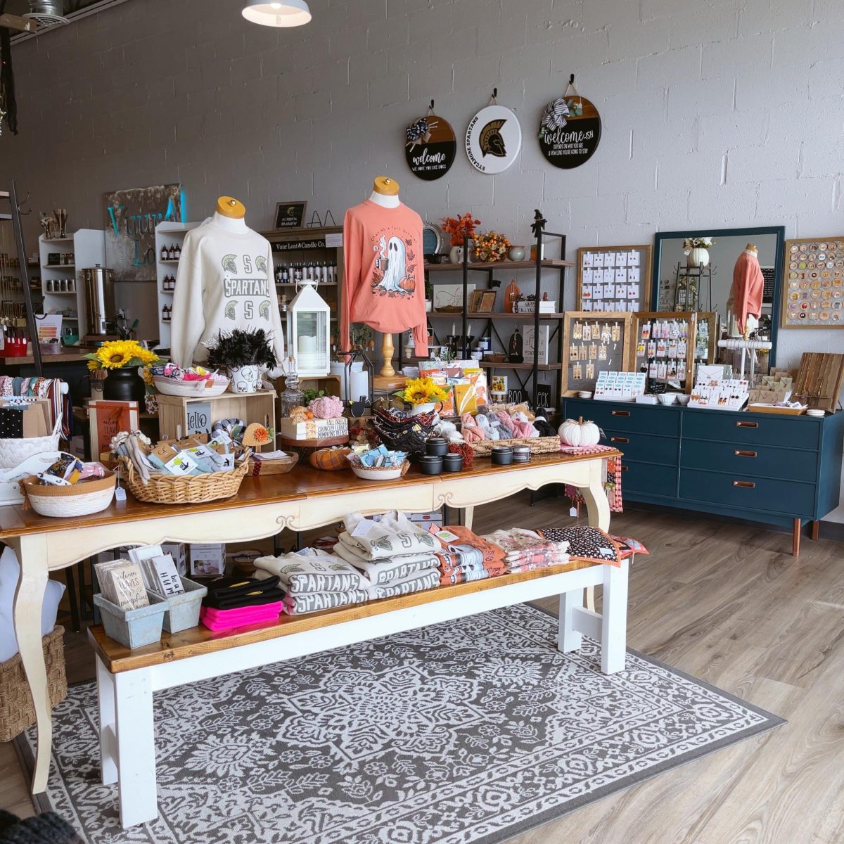 A table holds shirts and various items for sale. The Makers Collective is a small business that sells handmade goods. (Courtesy of Joni Peterson)