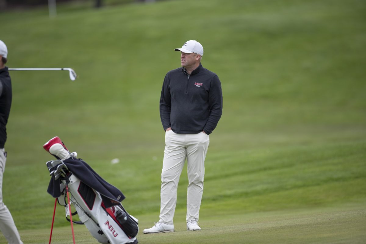 NIU men's golf head coach John Carlson eyes down an NIU golfer's shot. After wrapping up the fall season on Oct. 27, Carlson announced the signing of three recruits for the 2025 season on Tuesday. (Photo courtesy of NIU Athletics)