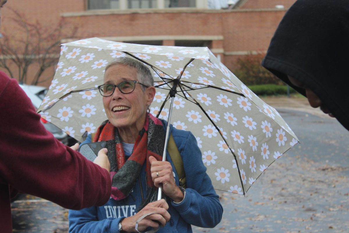 Kate McCabe, a DeKalb resident, smiles while holding an umbrella. The Barsema Alumni and Visitor’s Center is open from 6 a.m. to 7 p.m. for voting. (Nia Jackson | Northern Star)