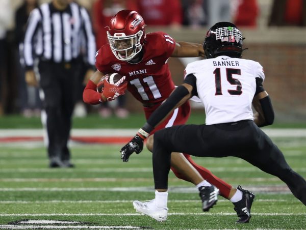 Miami University redshirt sophomore wide receiver Javon Tracy (11) runs after the catch as NIU redshirt freshman safety Santana Banner (15) approaches to make a tackle during Tuesday night’s Mallory Cup rivalry game at Fred C. Yager Stadium in Oxford, Ohio. Banner was ejected from the game for targeting near the end of the second quarter as the Huskies suffered their fourth consecutive loss to the RedHawks. (Courtesy of Miami Athletics)