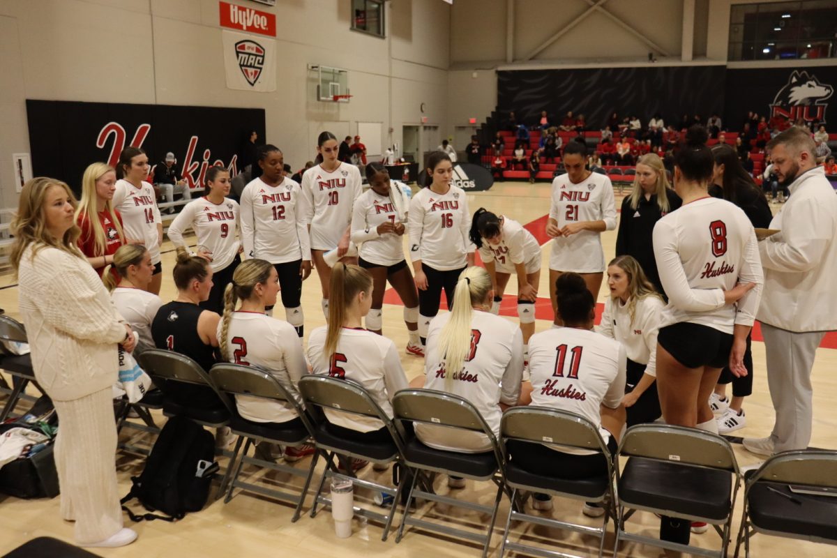 The NIU volleyball team huddles at its bench on Nov. 8 at Victor E. Court. Despite strong individual player performances, the Huskies finished 2024 with their lowest win total in program history. (Marco Alvarez | Northern Star)