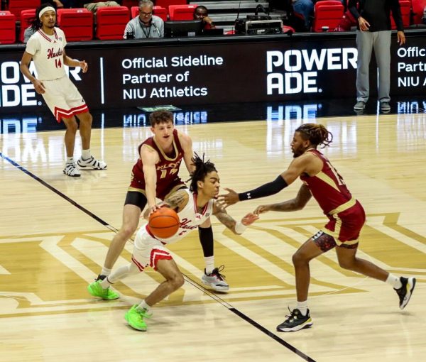 NIU men’s basketball sophomore guard Kailon Nicholls fends off two Elon University defenders Wednesday in the Huskies’ 75-48 loss. Nicholls finished with 2 points Saturday in NIU’s 98-52 loss against Elon University. (Marco Alvarez | Northern Star)