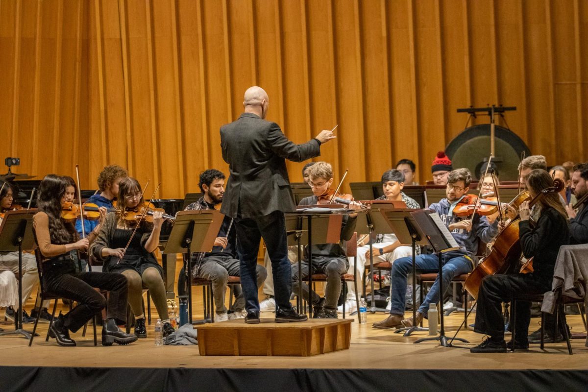 Members of the NIU Orchestra rehearse in the Boutell Memorial Concert Hall on Wednesday. Silas Huff is the director of the NIU Philharmonic and Opera Orchestras and has been at NIU since Fall 2023. (Tim Dodge | Northern Star)