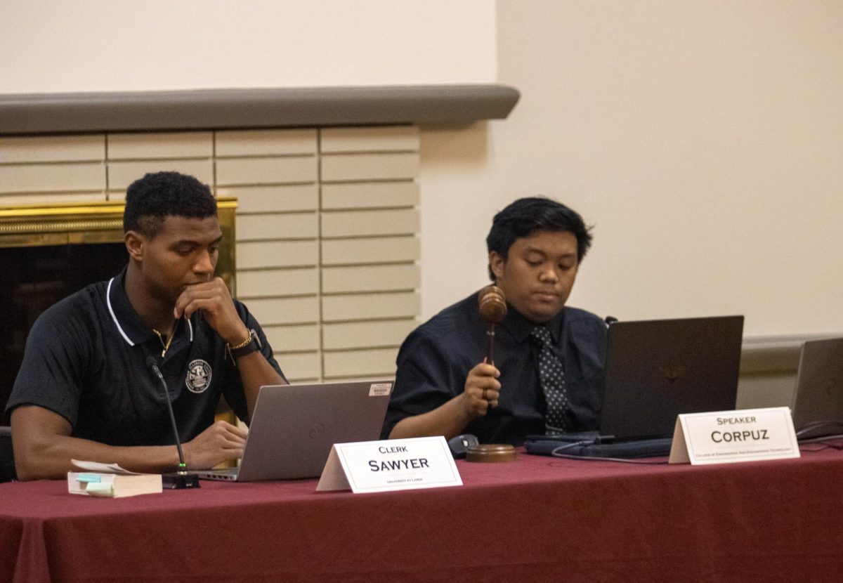 Speaker Manny Corpuz and Clerk Cameron Sawyer sit at a table while Speaker Corpuz bangs the gavel on the table. Senator Matt Robinson was dismissed from the SGA Senate Friday due to accumulating too many absences. (Tim Dodge | Northern Star)