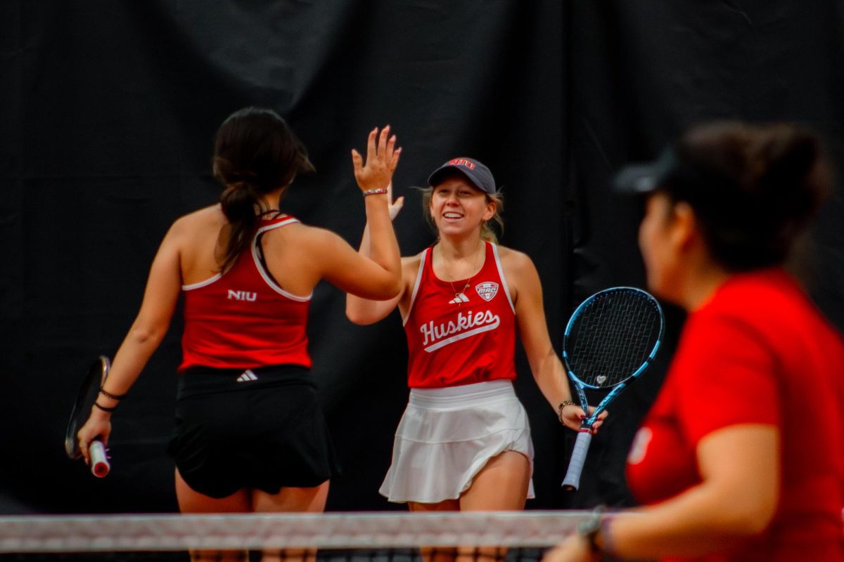 Freshman Irmak Budak (left) and junior Jenna Horne (right) high five after earning the point against Lewis University. NIU women's tennis won 29 of 32 matches at the NIU Huskie Invitational from Friday to Sunday. (Totus Tuus Keely | Northern Star)