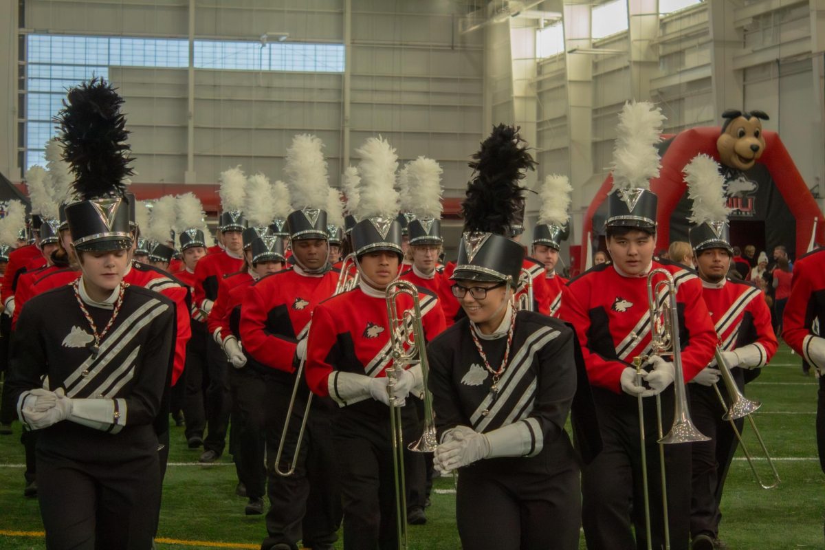 The NIU marching band marches into position in front of the Huskie Athletic Fund presentation and the wall of people formed to watch the performance. Saturday’s The Yard featured a DJ instead of a live performance in addition to the marching band’s rally. (Totus Tuus Keely | Northern Star)
