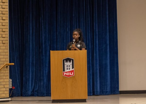 Ashley Johnson, SGA's chief of staff, stands behind a podium and addresses the crowd during the state of the SGA address held at noon Wednesday in the Sandburg Auditorium located in the Holmes Student Center. During the event, Johnson introduced each speaker before they gave their addresses. (Tim Dodge | Northern Star)