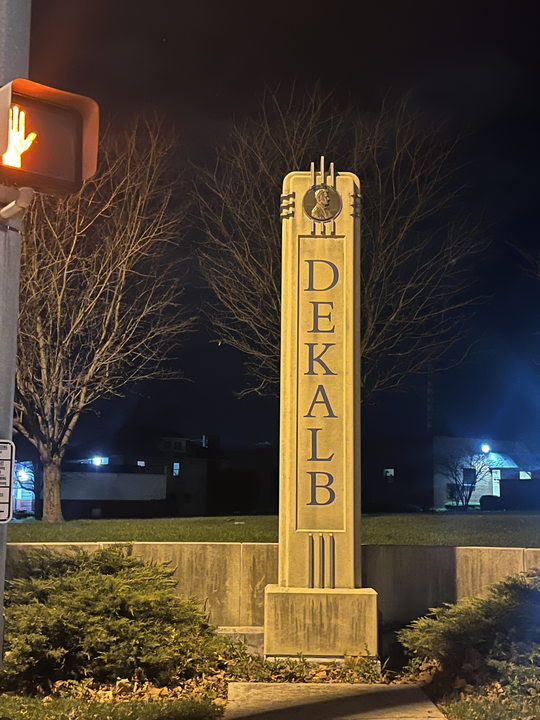 A vertical, columnar statue reads “DeKalb” with the circular penny emblem at its top. Which iconic small town spot in DeKalb gives you the most feels? (Sofia Didenko | Northern Star)