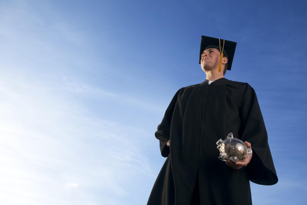 An image shows a college graduate holding a piggy bank. On Friday, NIU students received an email notification that MAP grant amounts would be reduced by 8%. (skodonnell via Getty Images) 