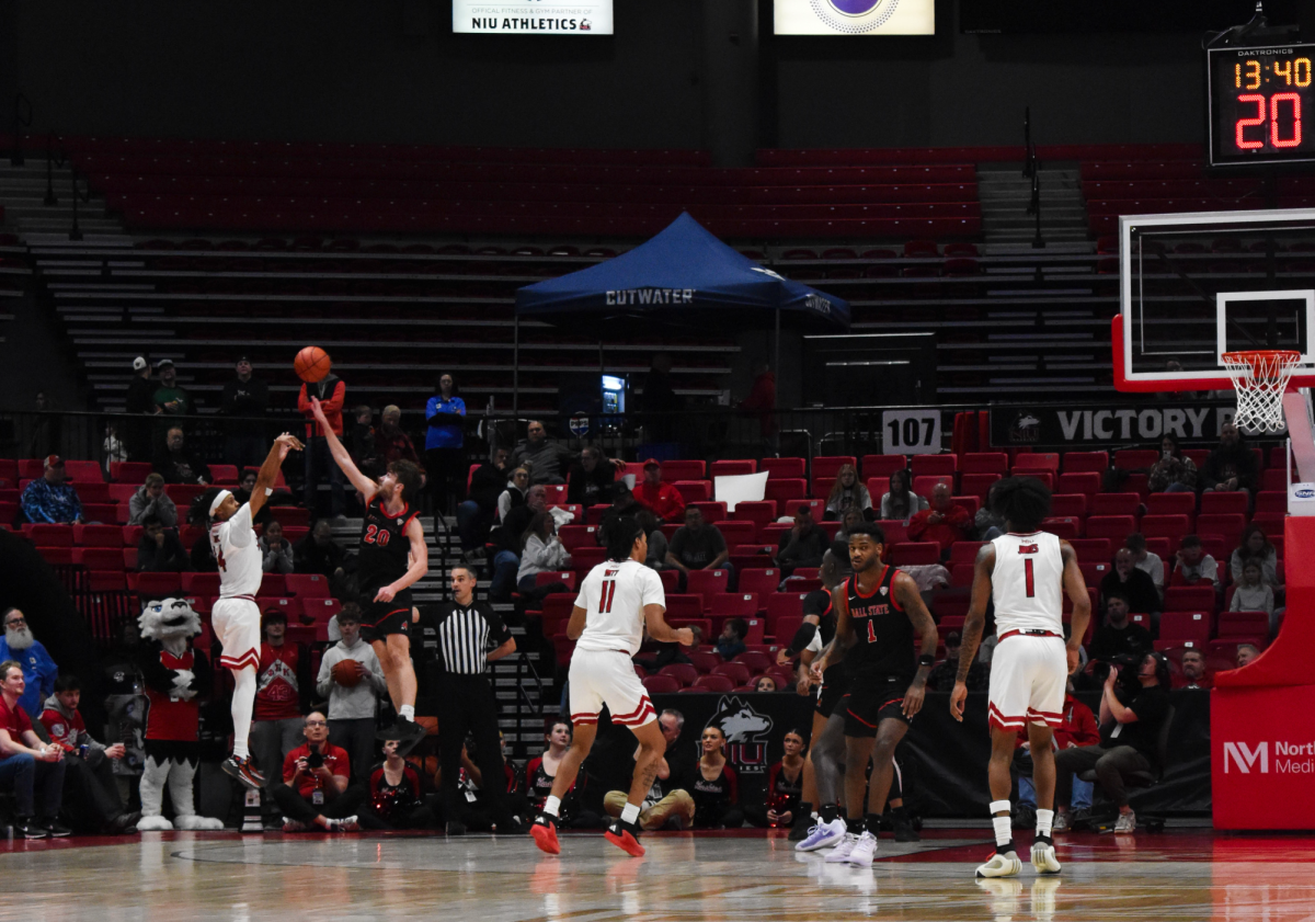 NIU senior guard James Dent Jr. (14) attempts a 3-pointer against Ball State University sophomore guard Joey Hart (20) during a Mid-American Conference men’s basketball game between the Huskies and Cardinals on Saturday inside the Convocation Center in DeKalb. Dent finished with 18 points and 10 rebounds to achieve the first double-double of his NIU career. (Erin Marie Barker | Northern Star)