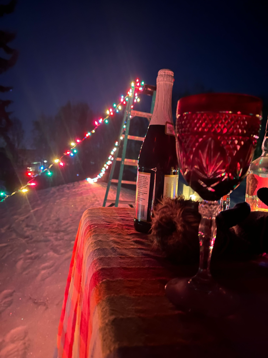 Christmas lights, a ladder and a table with sparkling apple cider and a cup are shown on top of Opinion Columnist Lucy Atkinson’s roof in Anchorage, Alaska. As part of her New Year’s Resolutions, Opinion Columnist Lucy Atkinson wants to work on her anxiety regarding unexpectedly losing loved ones. (Lucy Atkinson | Northern Star)