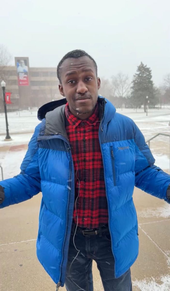 Jonathan Shelby stands in front of the camera as snow falls. This Weekend Writeup features events such as CAB's "Glow at Holmes" and "The Big Sing." (Ryan Day | Northern Star)