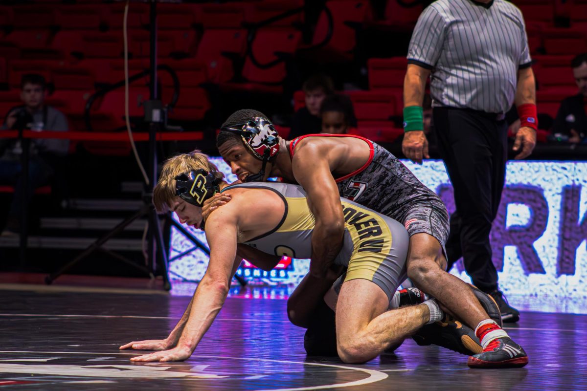 NIU wrestling redshirt sophomore Markel Baker holds Purdue University redshirt junior Dustin Norris from behind in the 133-pound match amid NIU's 29-8 loss against Purdue Jan. 12 at the Convocation Center in DeKalb. The Huskies overcame Ohio University by a score of 21-20 Saturday in Athens, Ohio. (Totus Tuus Keely | Northern Star)