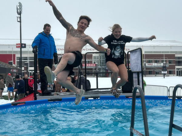 Two participants jump into a pool of freezing water during the Illinois Law Enforcement Torch Run Polar Plunge on Saturday at Huskie Stadium. The event kicked off more than a month of Polar Plunges set to be held across the state of Illinois. (Skyler Kisellus | Northern Star)