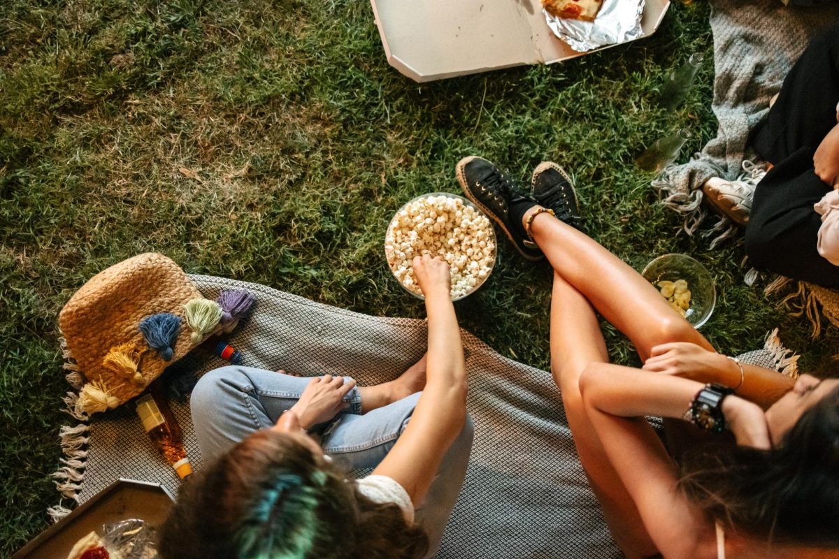 A woman reaches into a bowl of popcorn. Here are five movie recommendations to check out this summer. (Getty Images)