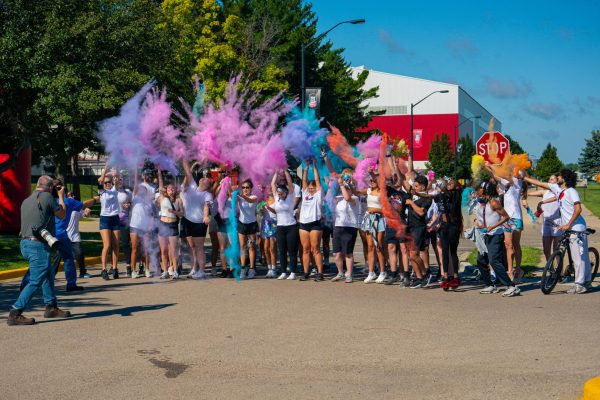 Color Run attendees launch packets of dyed corn starch into the air for an NIU promotional photo and video before the start of the event on Saturday. NIU gifted three sets of tickets to the Corn Fest carnival before the start of the Color Run to the attendees with birthdays closest to the stated dates. (Totus Tuus Keely | Northern Star)