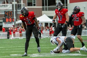 NIU redshirt senior safety Muhammed Jammeh (4) celebrates after tackling College of the Holy Cross senior wide receiver Max Mosey (13) for no gain during the first quarter of NIU’s season opener on Saturday at Huskie Stadium in DeKalb. Jammeh recorded NIU’s only takeaway of the game with an interception off a tipped pass in the first quarter. (Totus Tuus Keely | Northern Star)