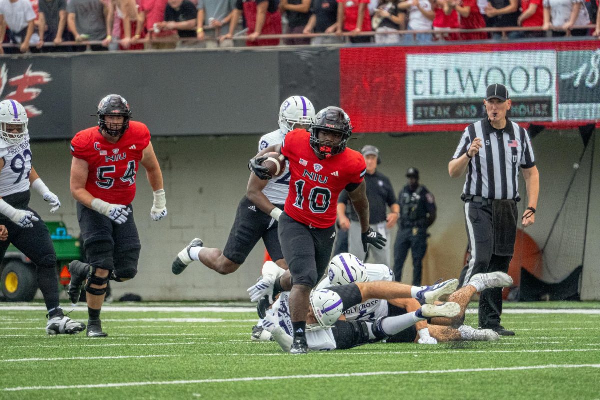 NIU senior running back Chavon Wright (10) shakes off a defender while running for a 45-yard gain during the first quarter of NIU's season opener against College of the Holy Cross on Saturday at Huskie Stadium in DeKalb. The run was the Huskies' longest of the game. (Totus Tuus Keely | Northern Star)