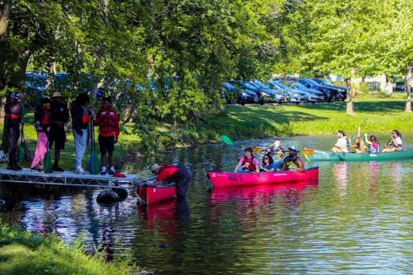 An Adventure Staff employee prepares a kayak for students as other kayakers line up to leave the East Lagoon. Attendees had to line up for several minutes in order to get a turn in the kayaks. (Ethan Rodriguez | Northern Star)