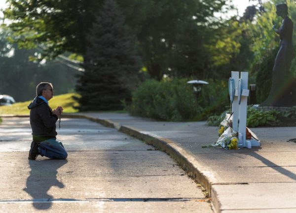 Mourner Tim Barr prays outside the Annunciation Church, which is a home to an elementary school and was the scene of a shooting that left children dead and injured, in Minneapolis, Minnesota. Opinion columnist Ethan Ernst argues that the government needs to take more action than just thoughts and prayers to stop mass shootings. (REUTERS | Tim Evans)
