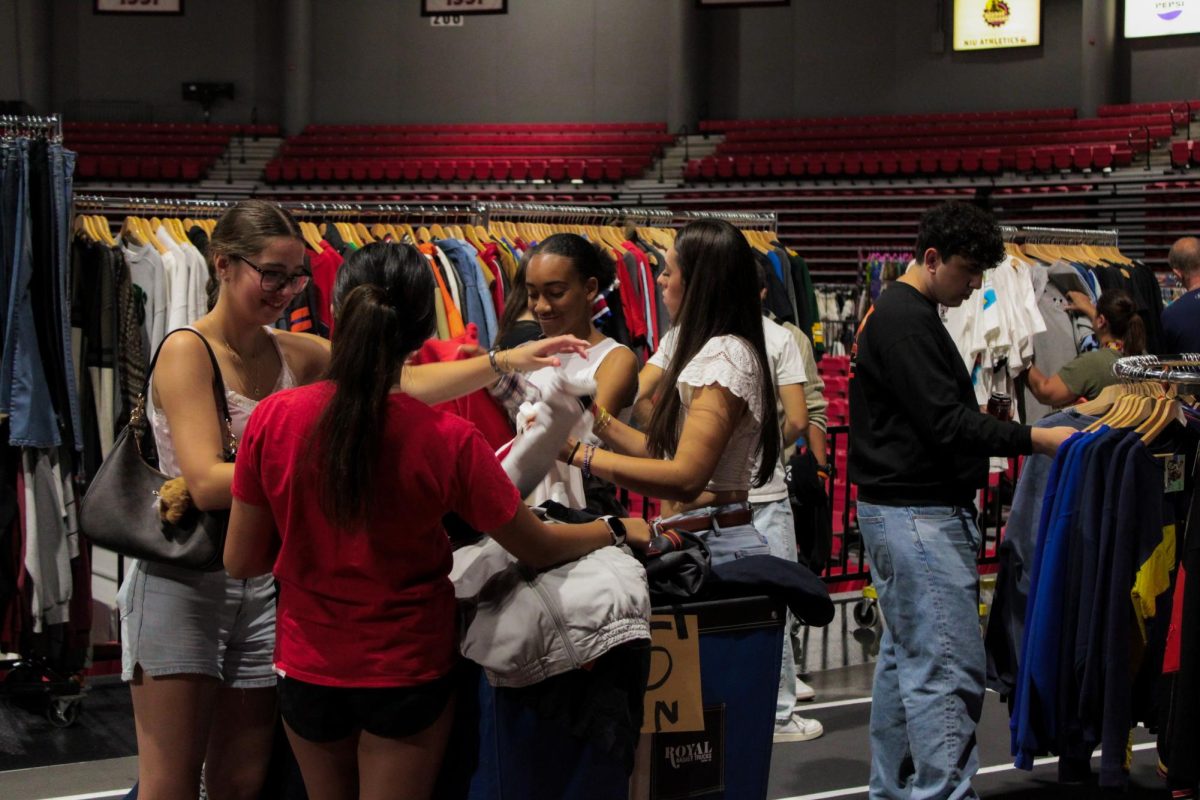 A group of Illinois Vintage Fest attendees rummage through the discounted clothing bin at one of the vendors. Some vendors offered discounted prices to attendees due to the rain that occurred during the set up of the event on Saturday. (Ethan Rodriguez | Northern Star)