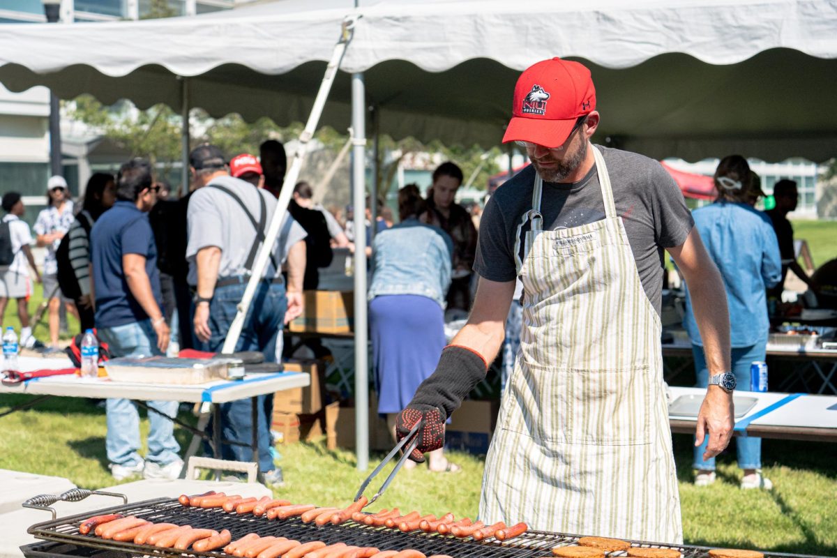 Nicholas Pohlman, a mechanical engineering professor, flips a hot dog on a grill during the CEET Cookout on Thursday at the East Lawn outside of the Engineering Building. The CEET Cookout ran from 11 a.m. until 1 p.m. (Totus Tuus Keely | Northern Star)
