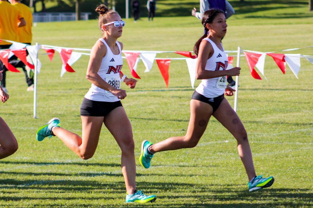 NIU cross country freshman runners Claire Hemilia (left) and Amelie Ojeda (right) run at the beginning of the 5K Huskie Invitational on Friday at the NIU North 40 Course. Ojeda was the first Huskie to finish the race, claiming fourth place with a time of 18:39.52. (Ethan Rodriguez | Northern Star)