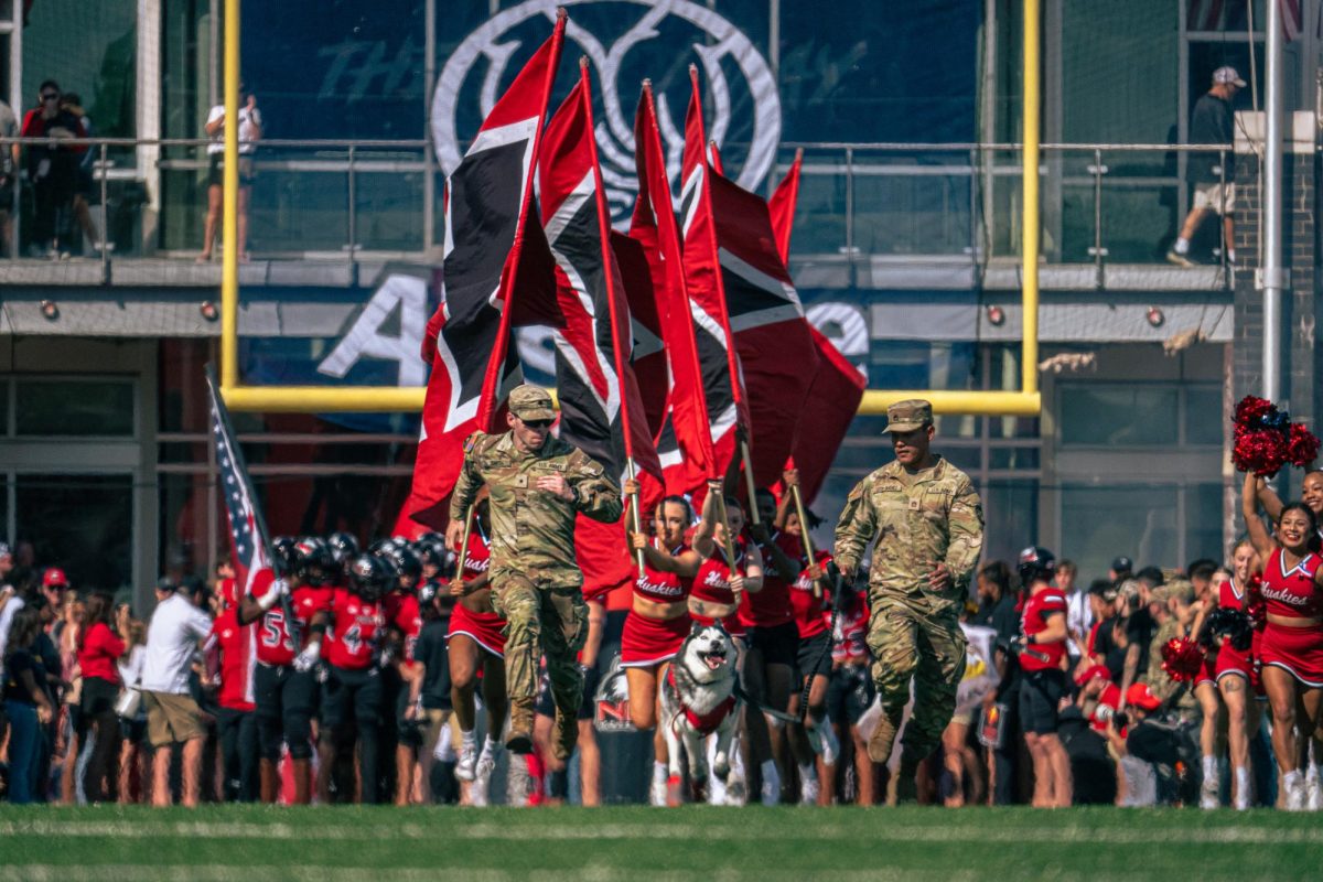 Army ROTC members, Mission III, NIU Cheerleaders and the football team enter the field before NIU faced San Diego State University on Saturday. Mission leads the pack during their entrance to the field each home game, running through the two lines of Huskie Marching Band members. (Totus Tuus Keely | Northern Star)