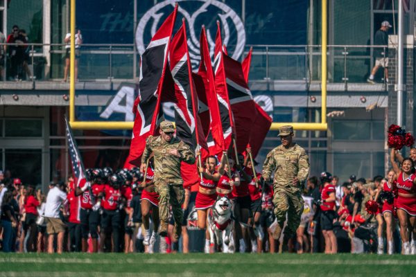 Army ROTC members, Mission III, NIU Cheerleaders and the football team enter the field before NIU faced San Diego State University on Saturday. Mission leads the pack during their entrance to the field each home game, running through the two lines of Huskie Marching Band members. (Totus Tuus Keely | Northern Star)