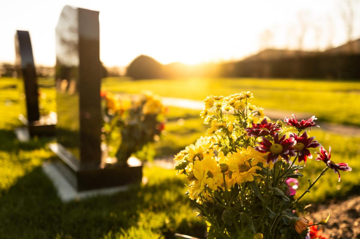 Flowers sit in front of marble headstones in a burial plot. Associate Professor Vera Lind centers her research around the topic of death. (Getty Images)