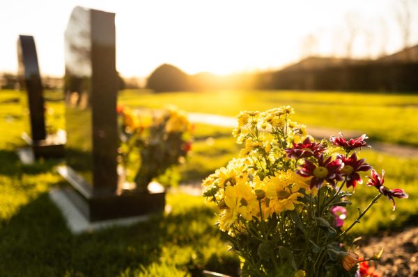 Flowers sit in front of marble headstones in a burial plot. Associate Professor Vera Lind centers her research around the topic of death. (Getty Images)