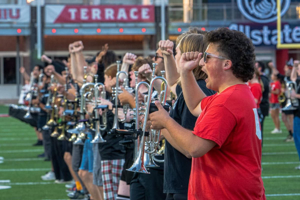 The Huskie Marching Band trumpets yell and spell “NIU” at the end of “Fight Song” during their practice on Thursday in the Huskie Stadium. The “Pride of the Midwest” will be joined by high school marching bands on Saturday during the football game against San Diego State University. (Totus Tuus Keely | Northern Star)