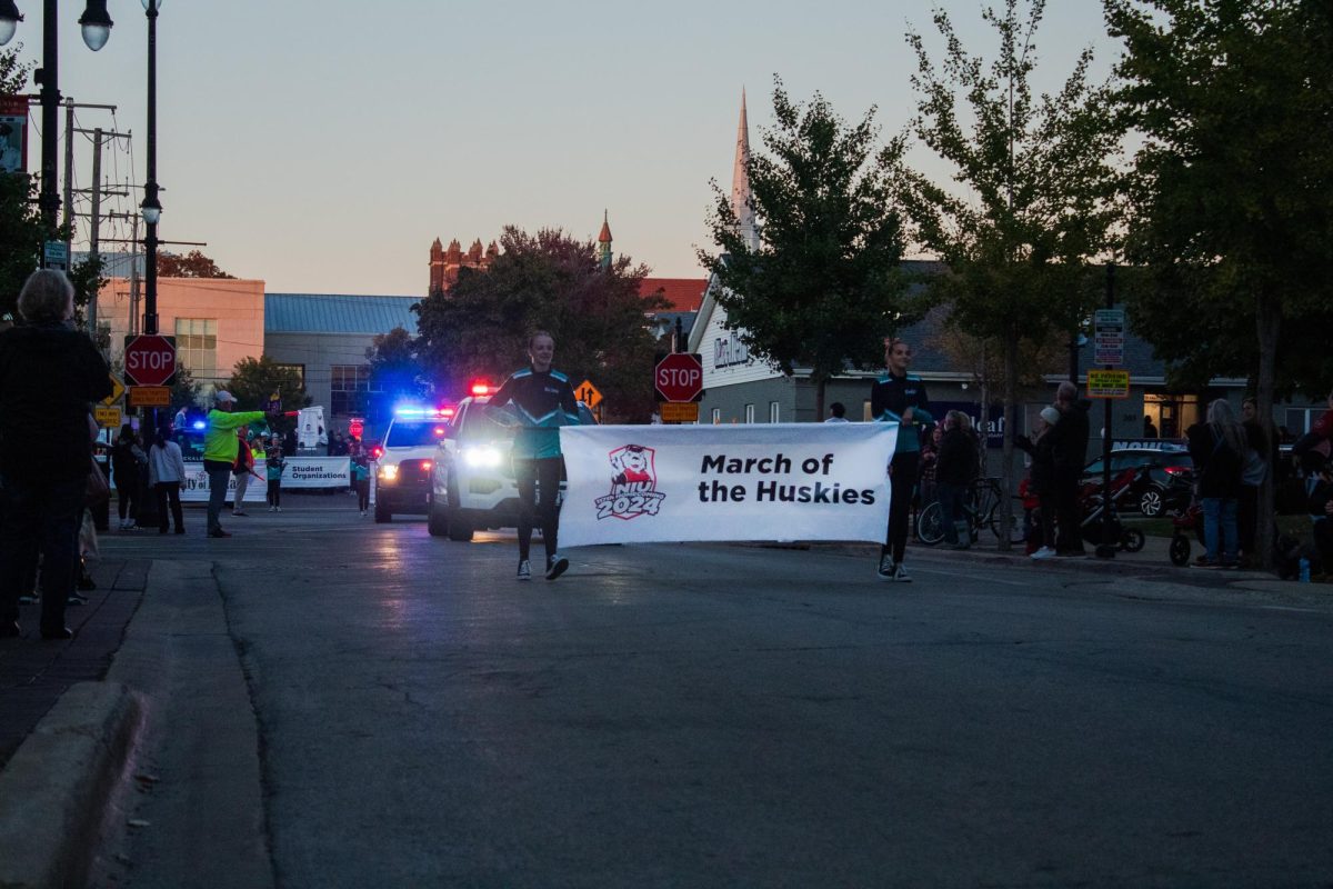 Student organizations march behind a “March of the Huskies” banner during the 2024 Homecoming celebration in downtown DeKalb. The event will return in 2025 at 6 p.m. on Thursday as part of NIU’s ongoing effort to make Homecoming welcoming for everyone. (Northern Star File Photo)